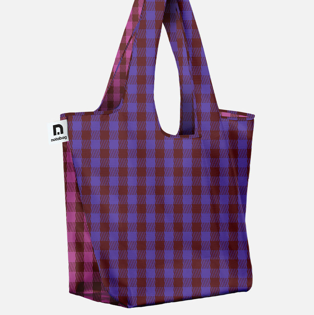 A reusable and foldable tote bag with a purple and dark red plaid pattern, featuring integrated shoulder straps - new JAM collection from notabag