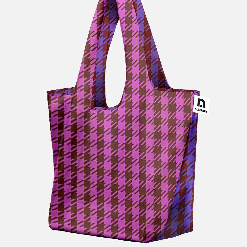 A foldable, spacious and reusable shopping tote bag with a pink and dark red plaid pattern, featuring two shoulder straps - new JAM collection from notabag
